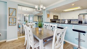 Una cocina moderna con armarios blancos, una isla central y una barra.