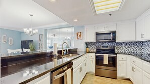 Una cocina moderna con armarios blancos, electrodomésticos de acero inoxidable y una isla grande con encimera negra.