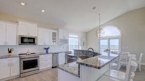 Una cocina moderna con armarios blancos, electrodomésticos de acero inoxidable y una isla grande con asientos.
