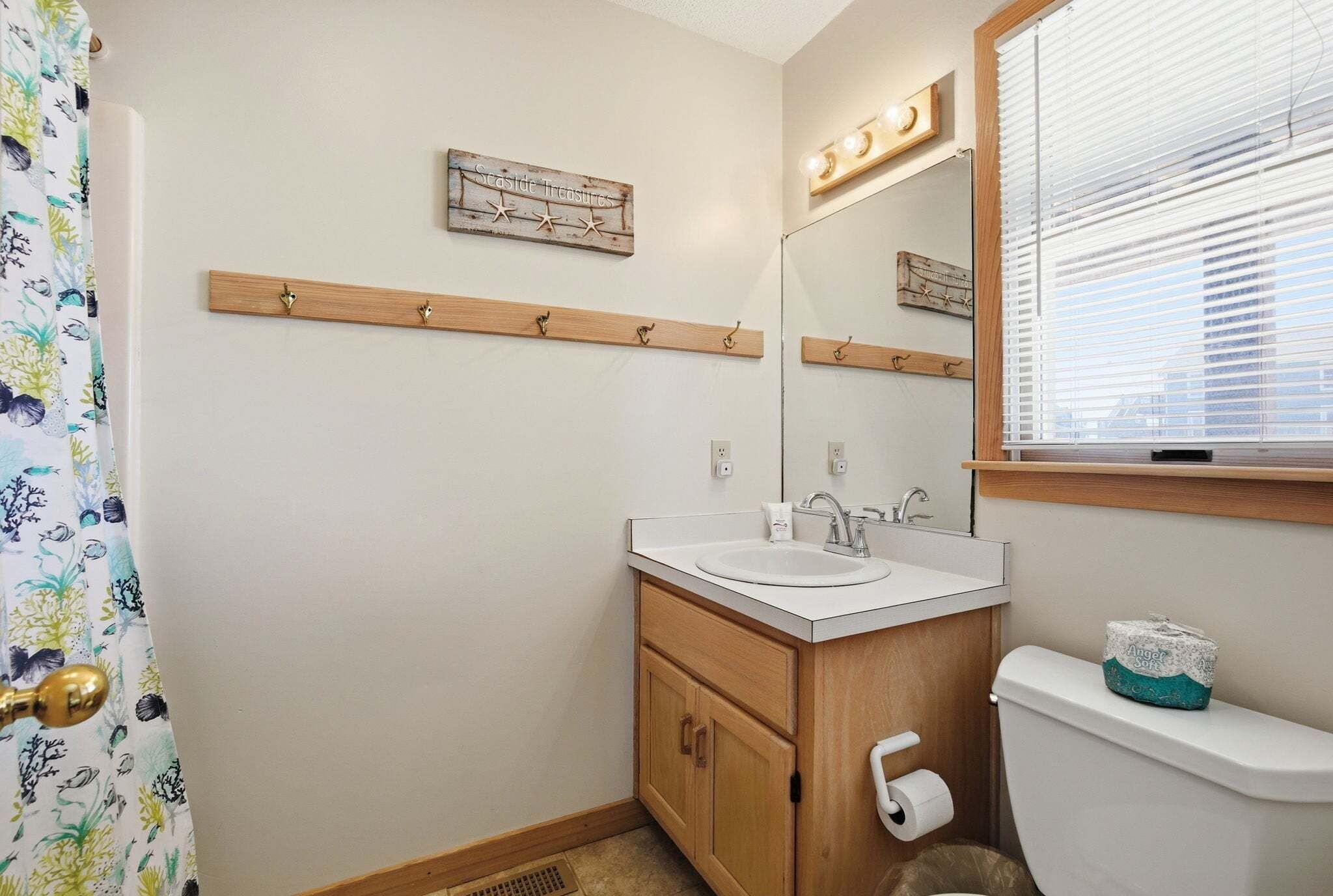 A bathroom with a wooden vanity, a sink, a toilet, a mirror, and a shower curtain.