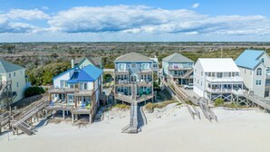 Ein Strandgrundstück mit mehreren Häusern, die durch Laubengänge verbunden sind, mit Balkonen und direktem Zugang zum Strand.
