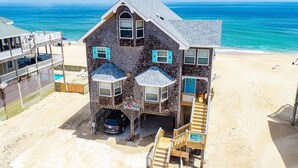 Ein Strandhaus mit Garage, einem Auto und einer Treppe, die zu einer Terrasse führt.