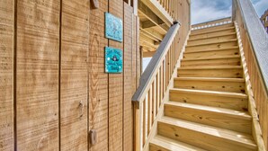 Eine Holztreppe mit Handlauf und einer Holzwand mit zwei Schildern.