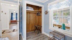 Ein Zimmer mit Holzschrank, Fenster mit Blick und einem kleinen Tisch.