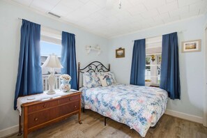 A bedroom with a bed, dresser, and curtains.