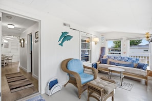 A spacious living area with a wicker chair, a sofa, and a small table.