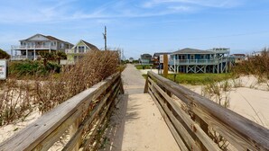 Un muelle de madera que conduce a propiedades frente a la playa con varios pisos y balcones.