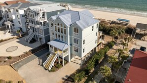 Ein mehrstöckiges Wohngebäude direkt am Strand mit Balkonen, einem überdachten Gang und Blick auf das Meer.