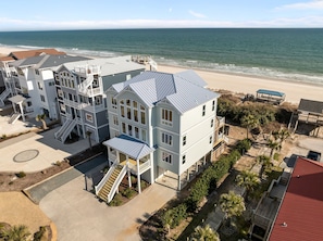 A beachfront multi-story residential building with balconies, a covered walkway, and a view of the ocean.