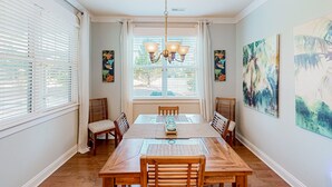 Ein Esszimmer mit Holztisch, Stühlen, einer Chandelierleuchtre und Kunstwerken an den Wänden.