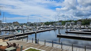 A marina with multiple docks and boats, wooden walkways, and houses in the background.