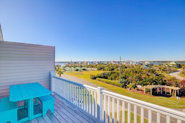 A balcony with a turquoise table and a view of a residential area with houses and greenery. - Multi-level duplex with beautiful ocean and Intracoastal views, elevator & pool (North Topsail Beach)
