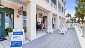 A property with a covered walkway, outdoor seating, and a sign indicating an agent on duty. - STJ22B: Coastal Condo with golf course view and shared pool access (Southport)