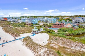 Un quartier résidentiel situé sur la côte, avec des propriétés donnant sur la plage, une promenade en bord de mer et un petit pavillon.