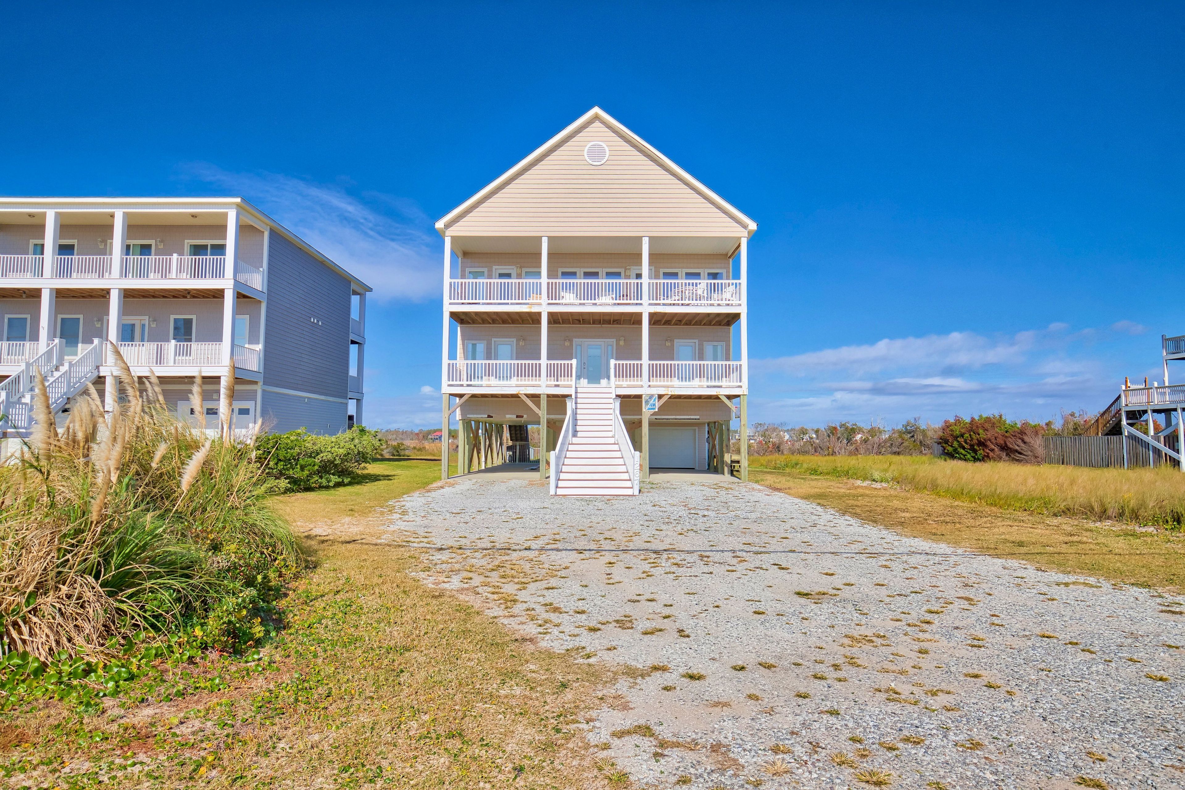 A beachfront hotel with a central building featuring a balcony and a covered entrance.
