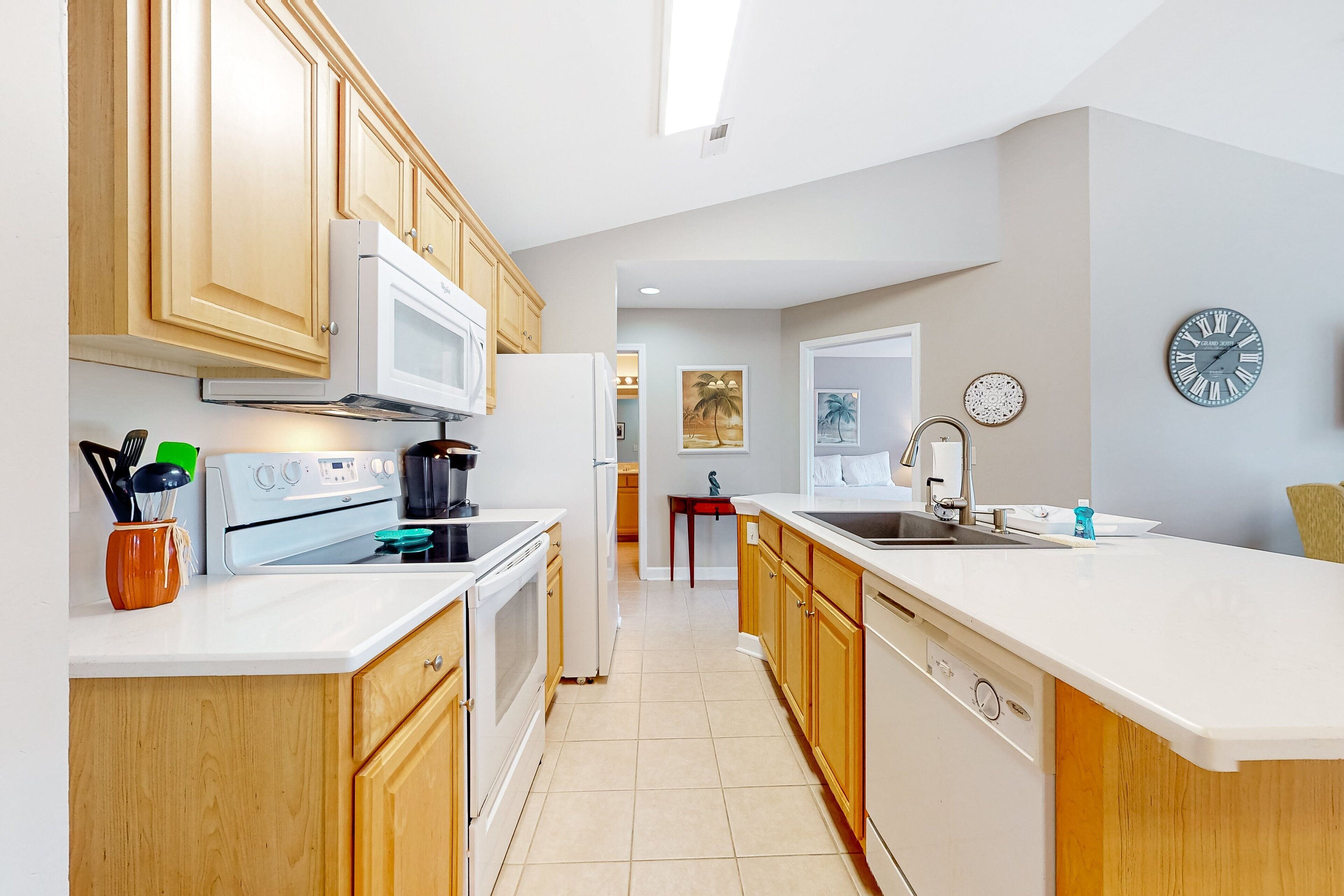 A modern kitchen with wooden cabinets, a white countertop, a microwave, stove, and a sink.