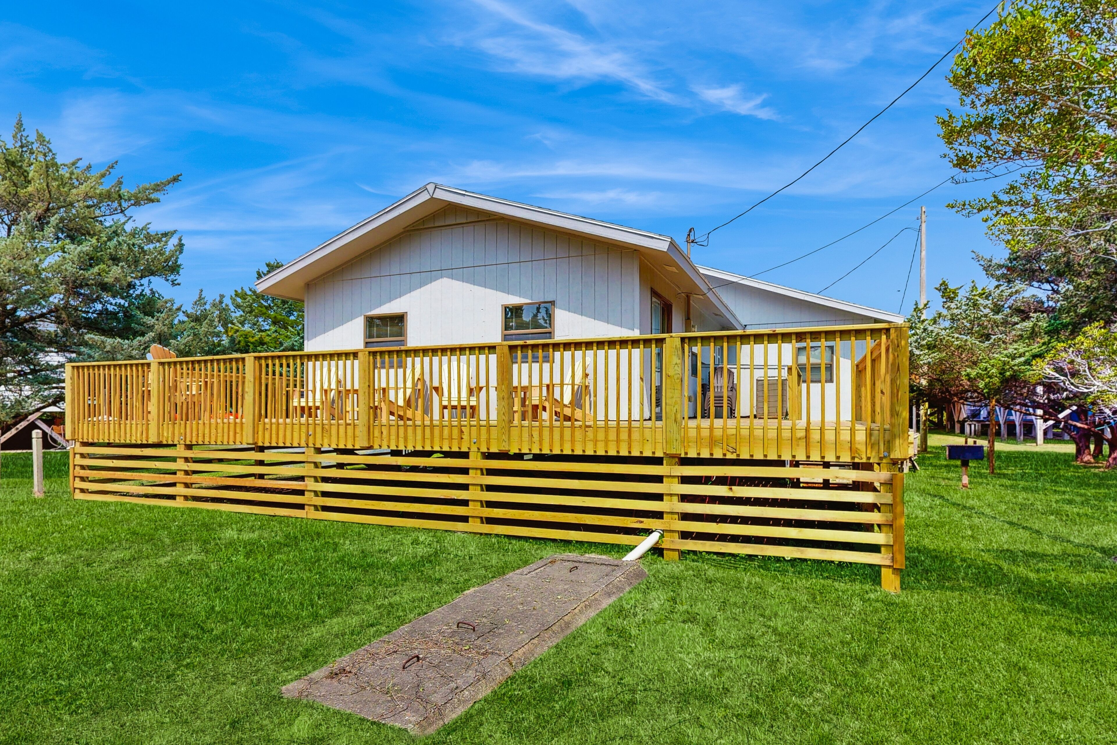 A white building with a wooden deck and a small porch.