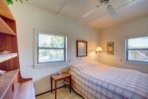 A bedroom with a bed, a desk, a lamp, and a ceiling fan. - Bugler's Holiday 352: Single-level, sundeck, walk to the beach (Avon)
