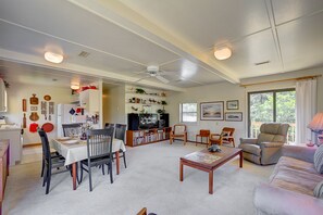 A spacious living room with a dining area, a television, and a large window with curtains. - Bugler's Holiday 352: Single-level, sundeck, walk to the beach (Avon)