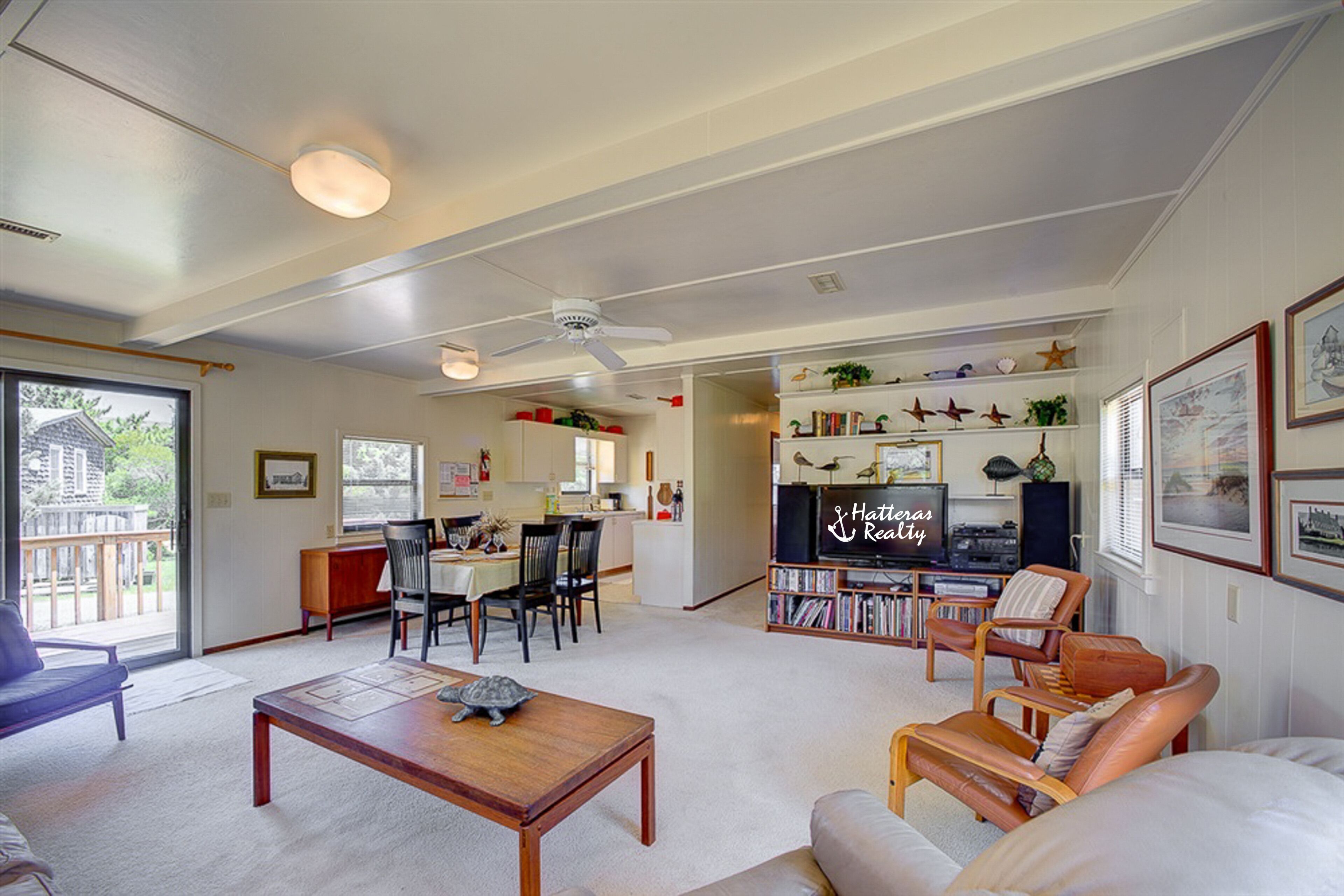 A spacious living area with a dining table, a sofa, and a television in the background.