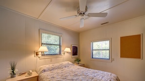 A bedroom with a bed, nightstand, lamp, and a ceiling fan. - Bugler's Holiday 352: Single-level, sundeck, walk to the beach (Avon)