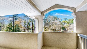 A covered outdoor area with a view of trees and a clear sky. - Colony II - Unit 509 at Oyster Bay condo | fast WiFi, seasonal pools, hot tub, fitness room (Sunset Beach)
