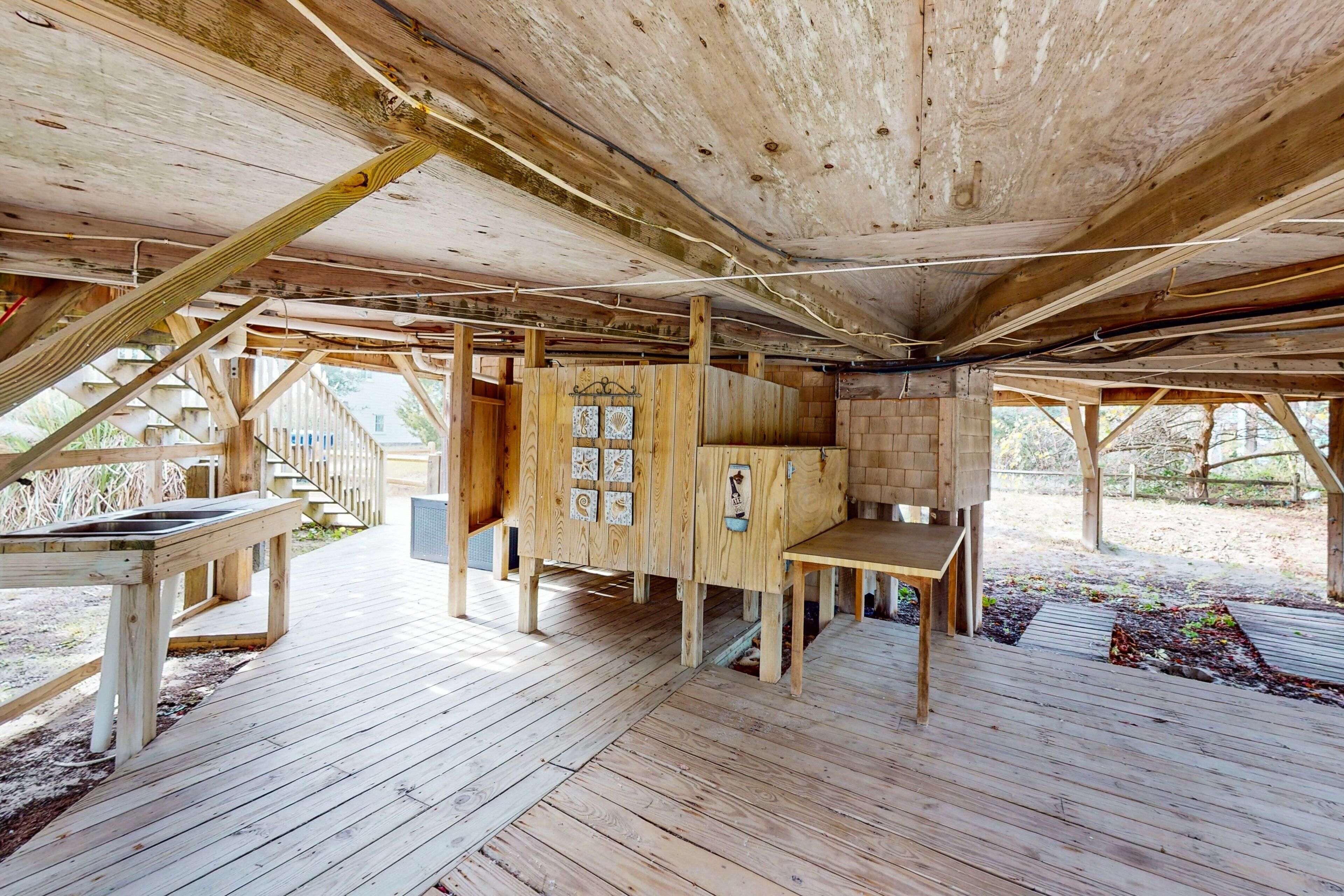 Una estructura rústica de madera con terraza, un banco incorporado y una pequeña mesa.