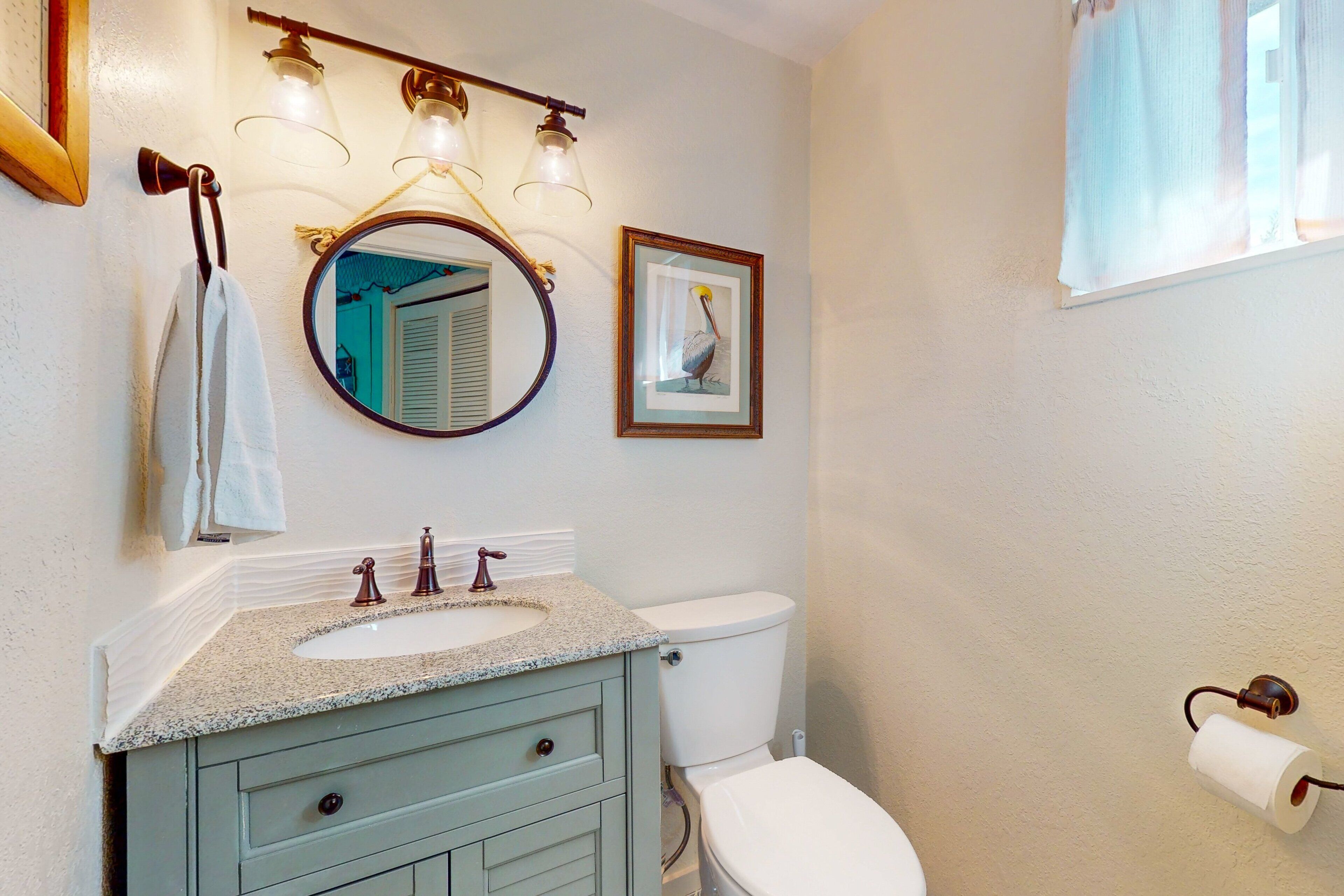 A bathroom with a sink, toilet, and a framed picture on the wall.