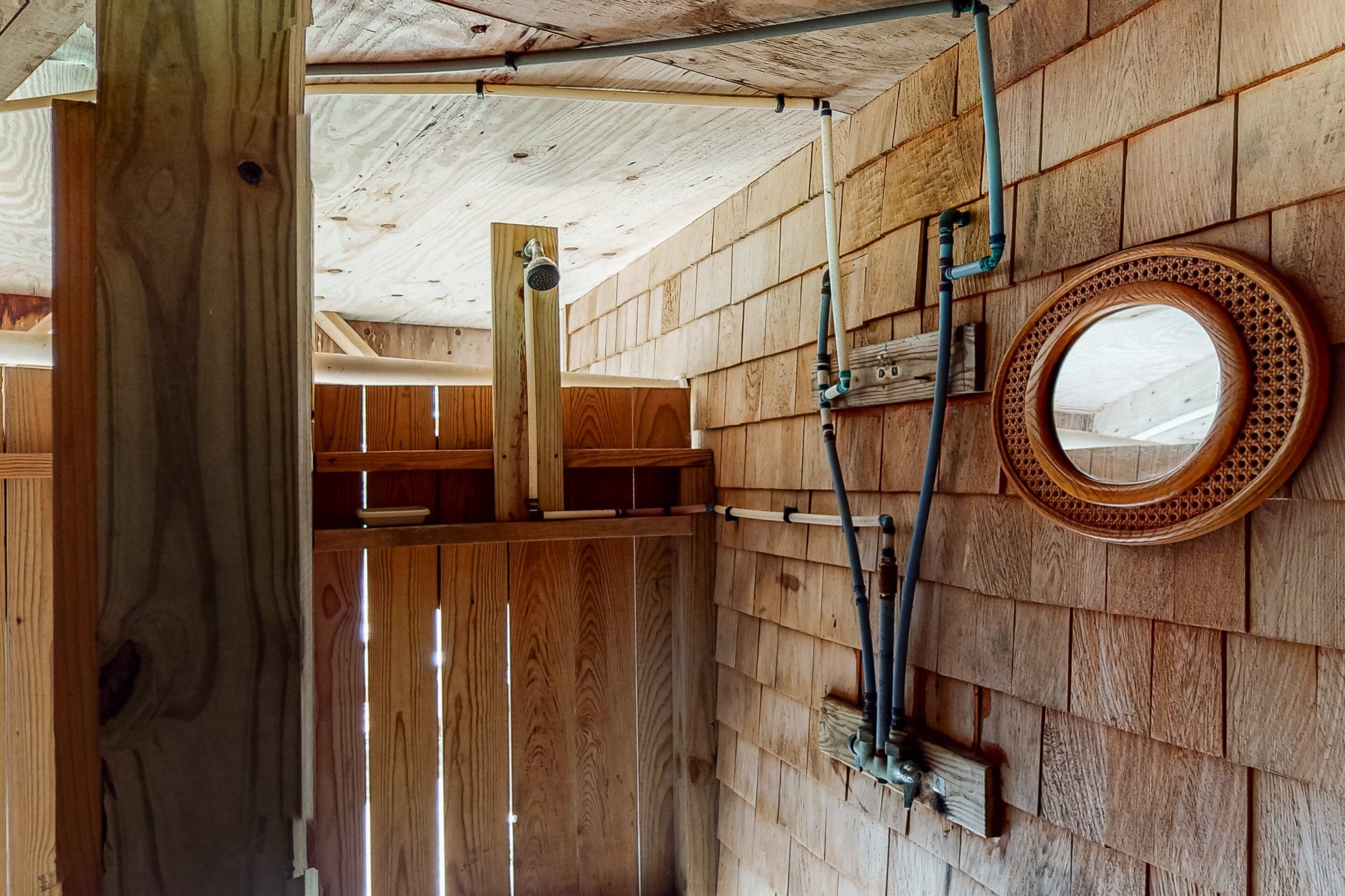 Un intérieur en bois, avec un plafond en bois, un mur en bois orné d’un miroir rond et un poteau en bois.