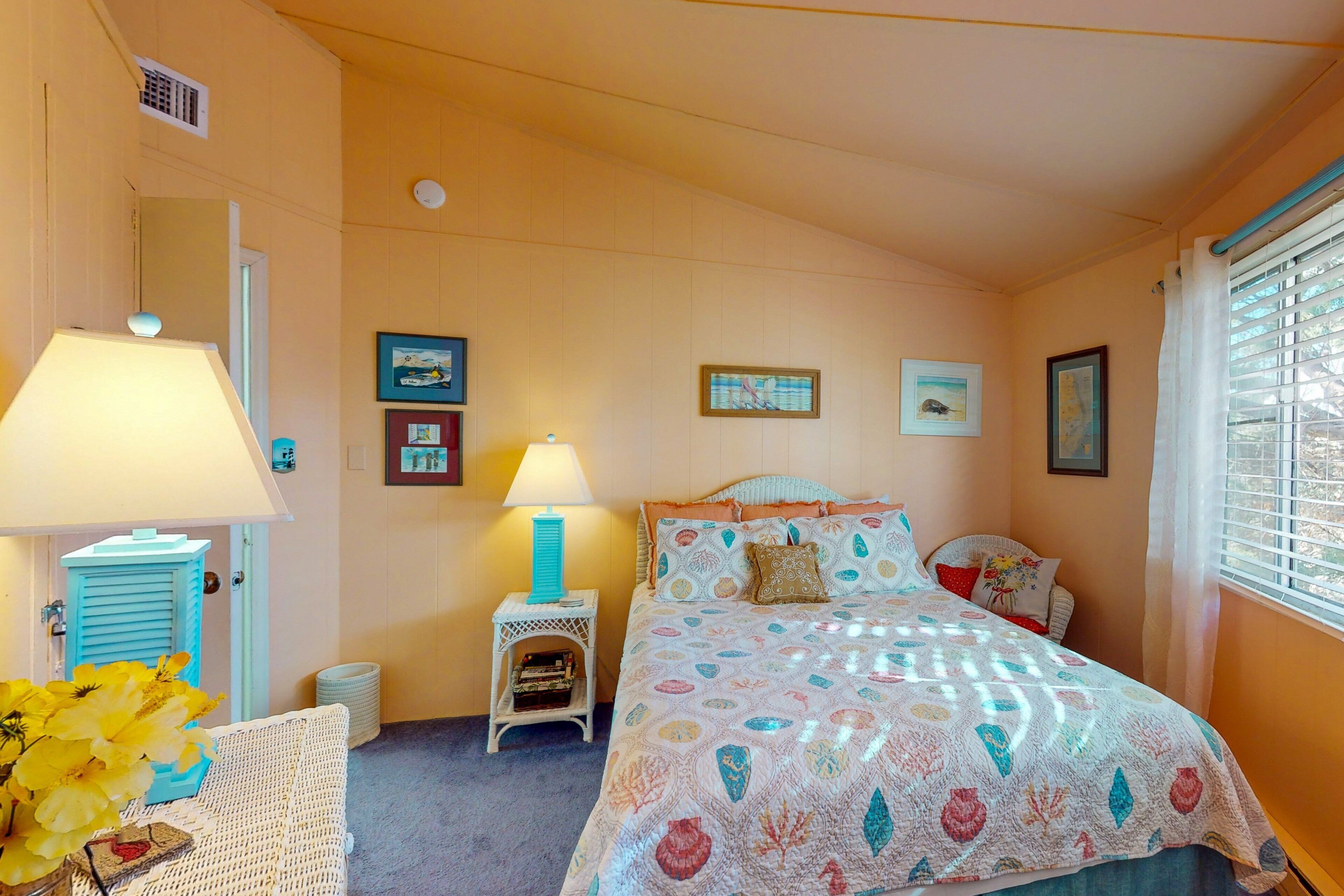 A bedroom with a bed, two bedside lamps, a small side table, and a chair.