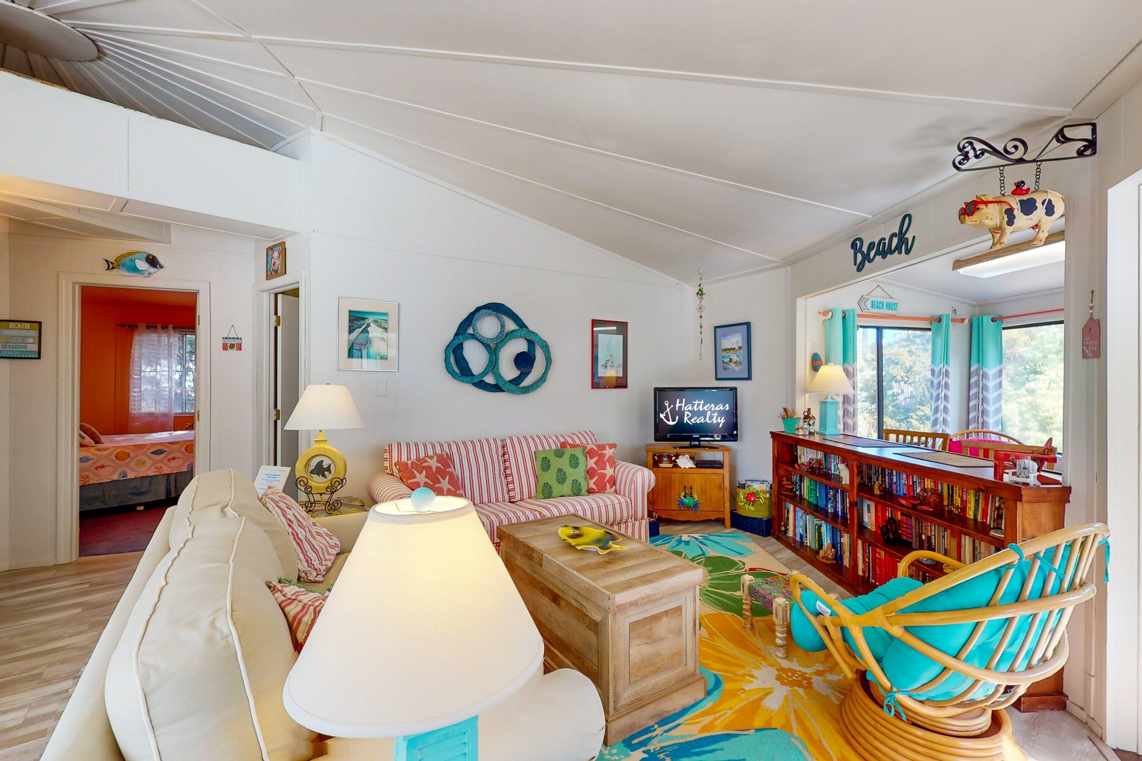 A cozy living room with a sofa, a wooden coffee table, a bookshelf, and a television.