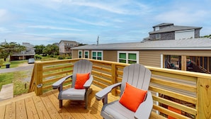 Una terrazza con poltrone Adirondack e ringhiera in legno che si affaccia su una zona residenziale.