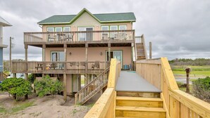 A two-story building with a balcony and a wooden staircase leading to the entrance. - Beachfront home with outdoor shower, 2 decks, central AC, & W/D - dogs ok (North Topsail Beach)