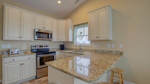 A kitchen with white cabinets, a granite countertop, stainless steel appliances, and a window with a view. - Beachfront home with outdoor shower, 2 decks, central AC, & W/D - dogs ok (North Topsail Beach)