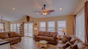 A spacious living room with a brown leather sofa, a wooden ottoman, and a ceiling fan. - Beachfront home with outdoor shower, 2 decks, central AC, & W/D - dogs ok (North Topsail Beach)