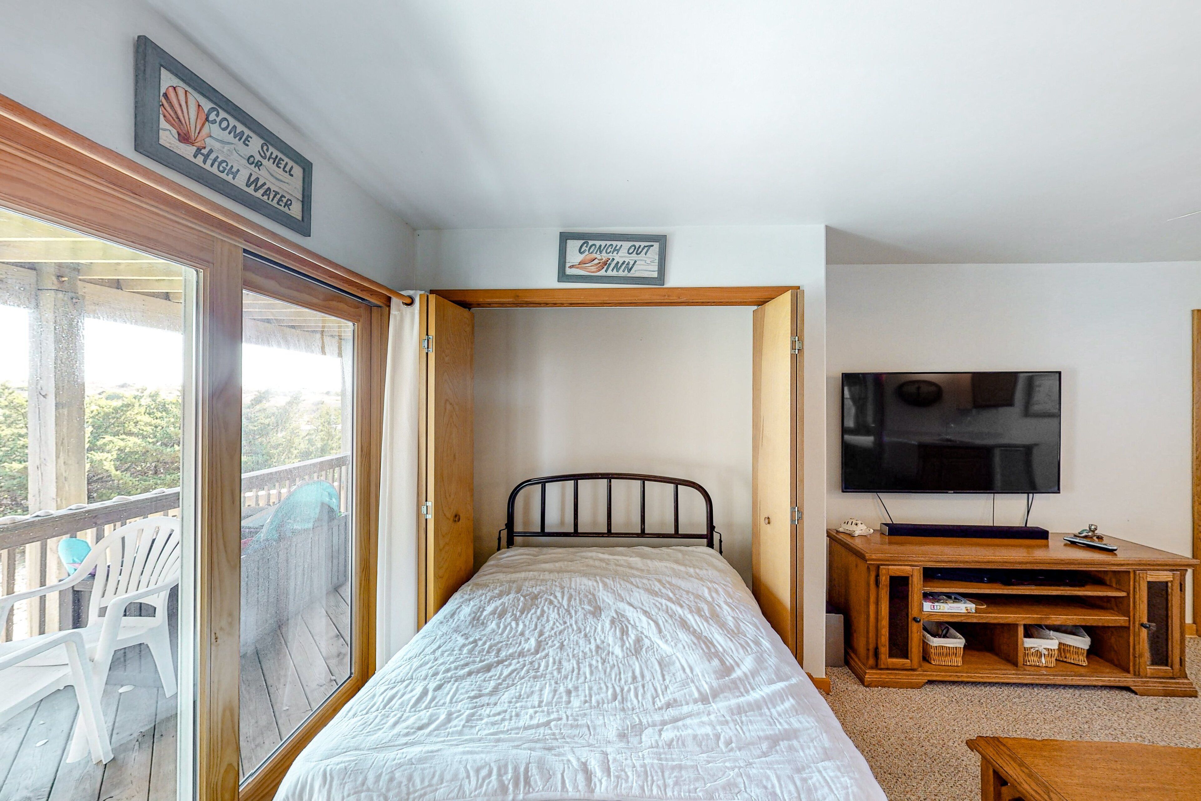A bedroom with a bed, a television, and a wooden TV stand.
