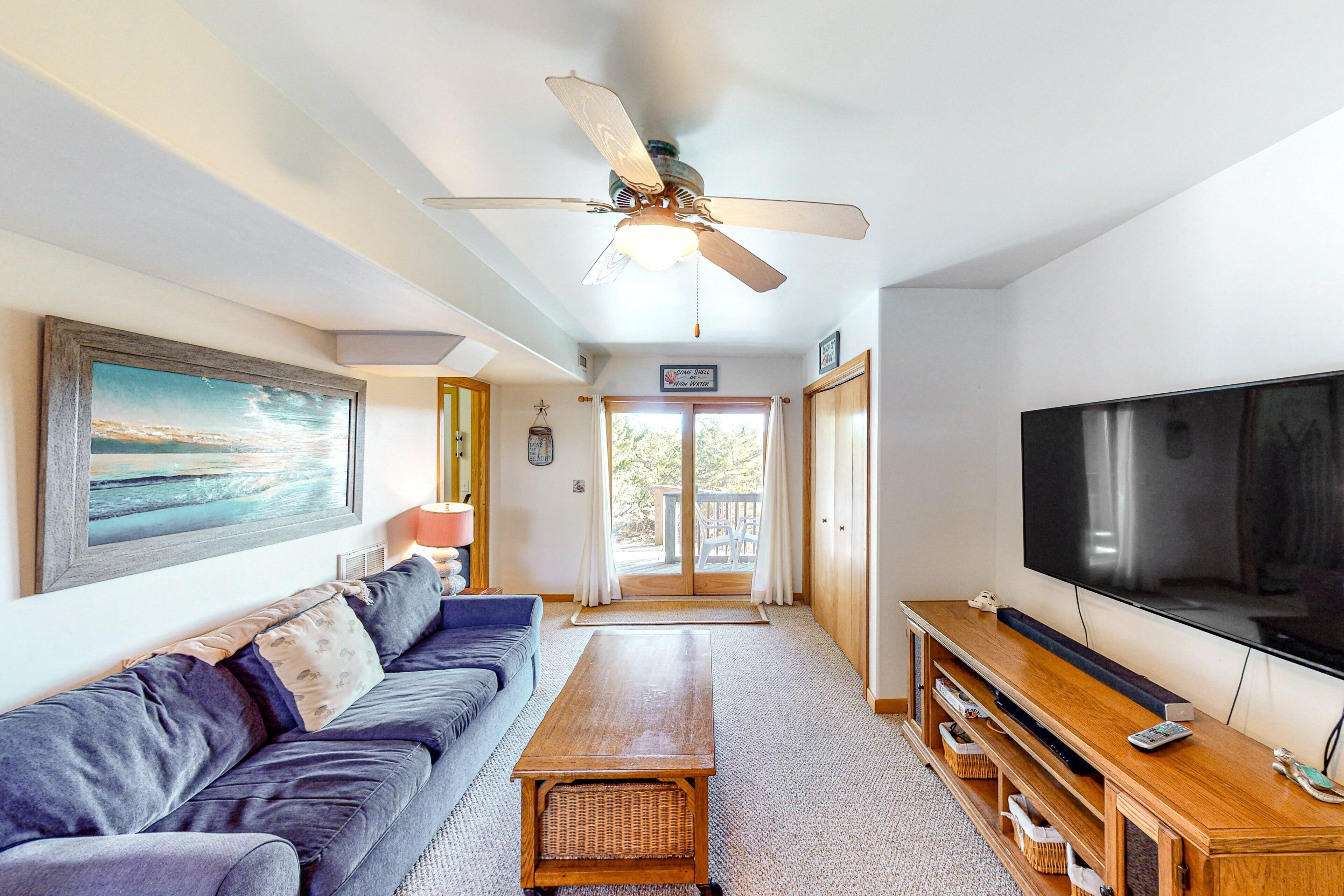A living room with a sofa, coffee table, TV, and ceiling fan.