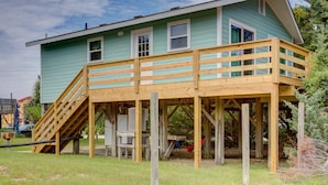 Una casa a due piani con una veranda in legno e una scala che conduce al piano superiore.