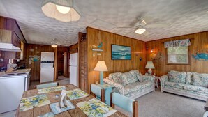Un accogliente soggiorno con soffitto in legno, un tavolo da pranzo con sottopiatti floreali e due divani a motivi floreali.