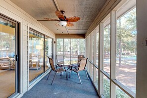 A covered outdoor area with a round table and chairs, large windows, and a ceiling fan. - Resort condo with A/C & near golf & beach - snowbird-friendly (Sunset Beach)