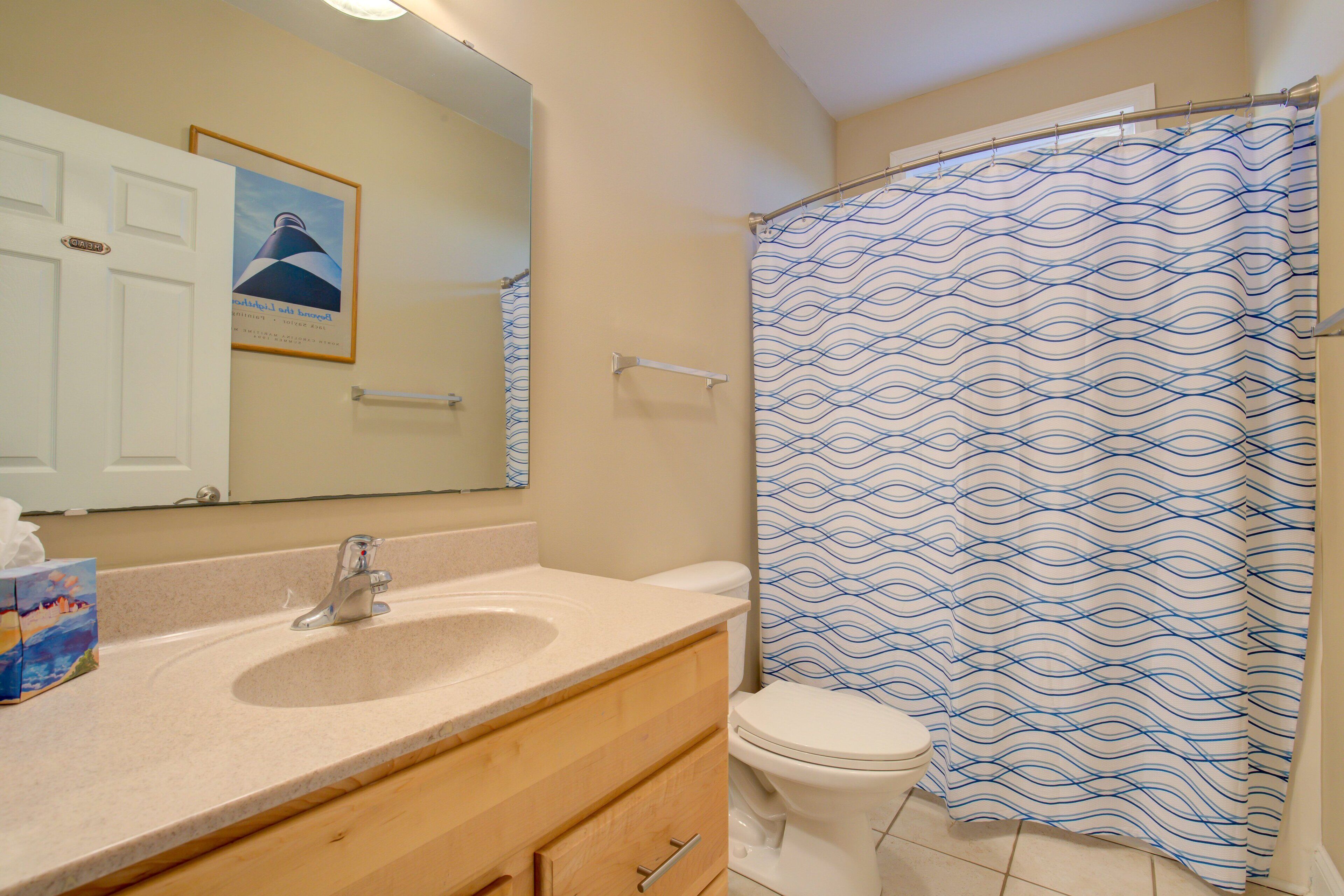 A bathroom with a sink, mirror, toilet, and shower curtain.