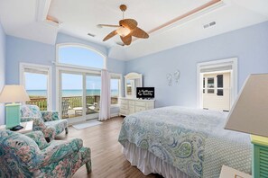 A bedroom with a large bed, a ceiling fan, a view of the ocean, and a sign for Hatteras Realty.