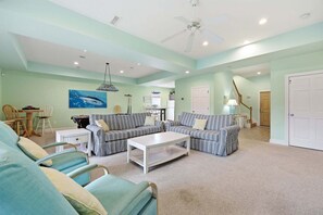 A spacious living room with a sectional sofa, a coffee table, and a dining area with chairs.