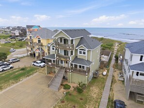 A multi-story beachfront property with a driveway, a parking area, and a view of the ocean.