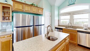Cucina con elettrodomestici in acciaio inossidabile, mobili in legno e un'ampia finestra che permette l'illuminazione naturale.