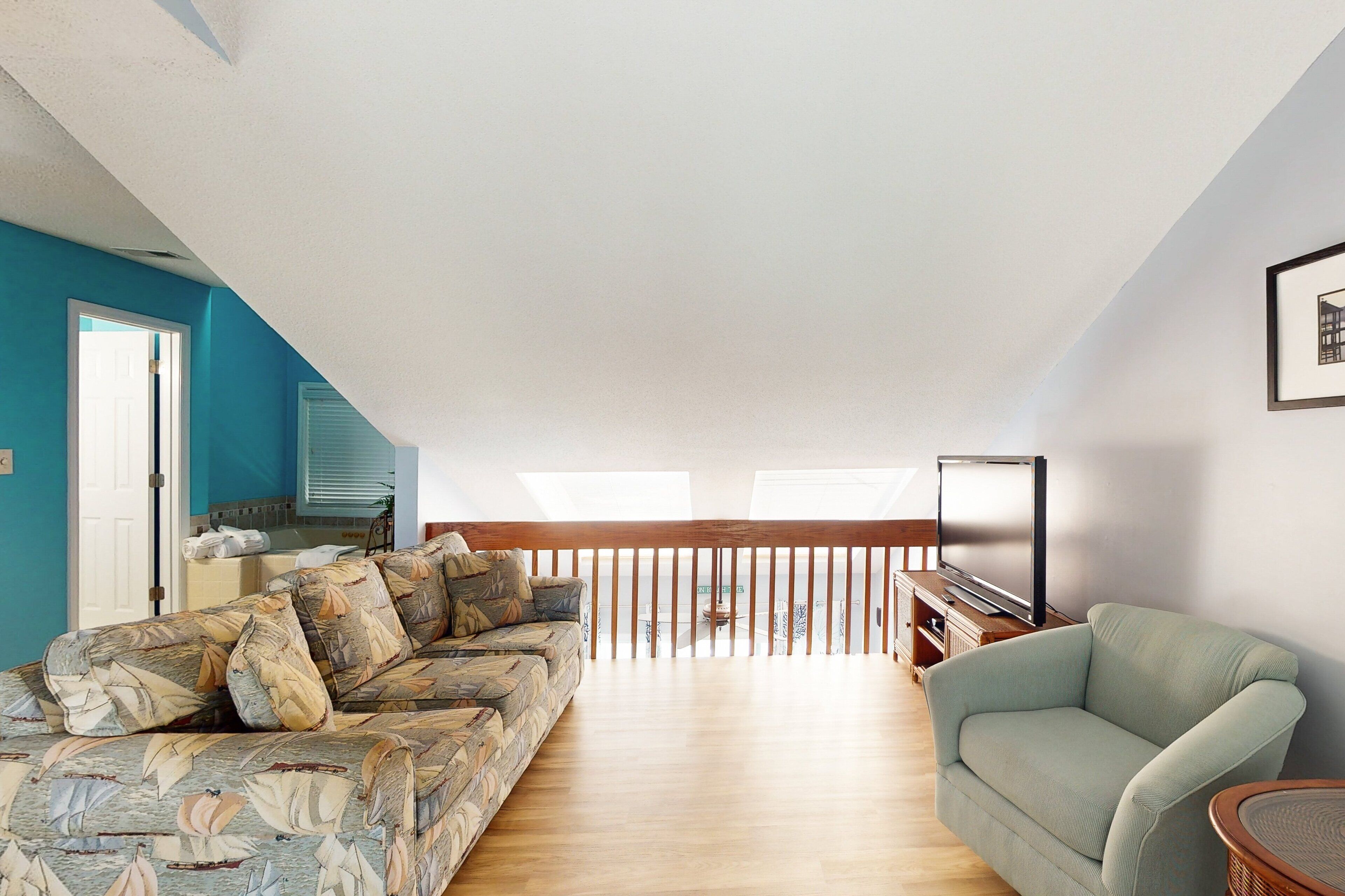 A spacious living area with a sofa, a green armchair, and a TV.