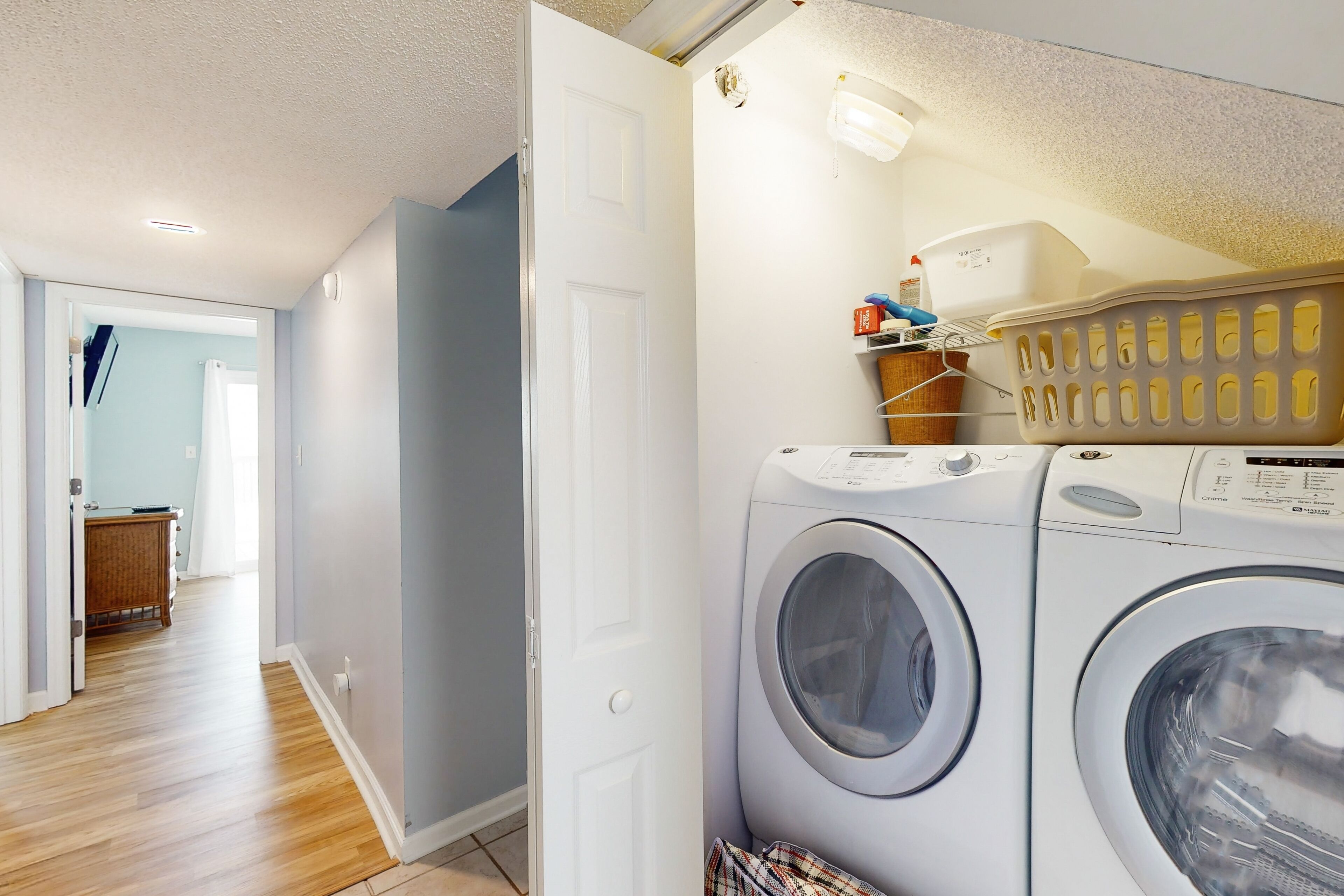 A laundry room with two front-loading washing machines, a drying rack, and a basket.