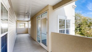 Un balcon abrité avec un plancher en bois, des portes-fenêtres coulissantes et une vue sur les environs.
