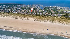 Vue aérienne d’une zone résidentielle côtière, avec des maisons, une plage et un emplacement clairement indiqué pour Hatteras Realty.