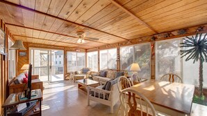 Un vaste espace de vie doté d’un plafond et de murs en bois, d’une table à manger et de sièges confortables.